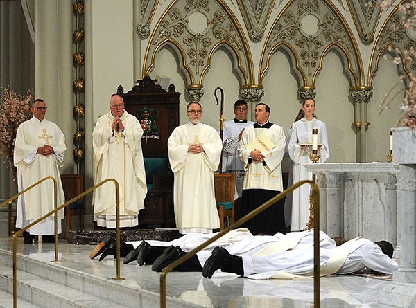 Bishop Richard Malone prays as candidates Luke Uebler, Cole Webster, Robert Agbo and Martin Gallagher lay prostrate during the Litnay of Supplication tduring the Ordination Mass at St. Joseph Cathedral. (Dan Cappellazzo/Staff Photographer)